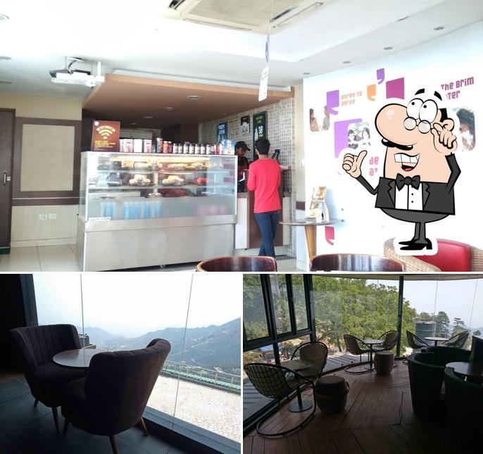 Take a seat at one of the tables at Cafe Coffee Day - The Mall Road